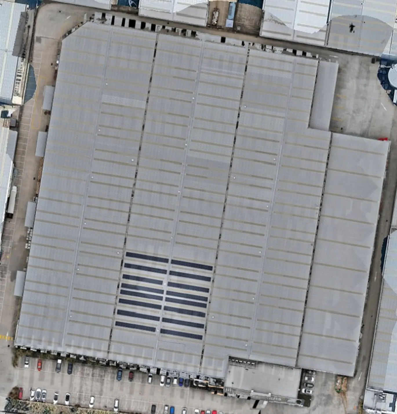 Colour aerial photo of Warehouse 2: a large grey metal roof with a small solar array near the bottom.